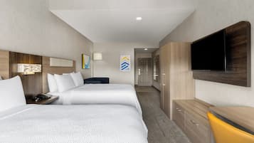 A hotel room with two beds, a TV, a desk, and a wardrobe.