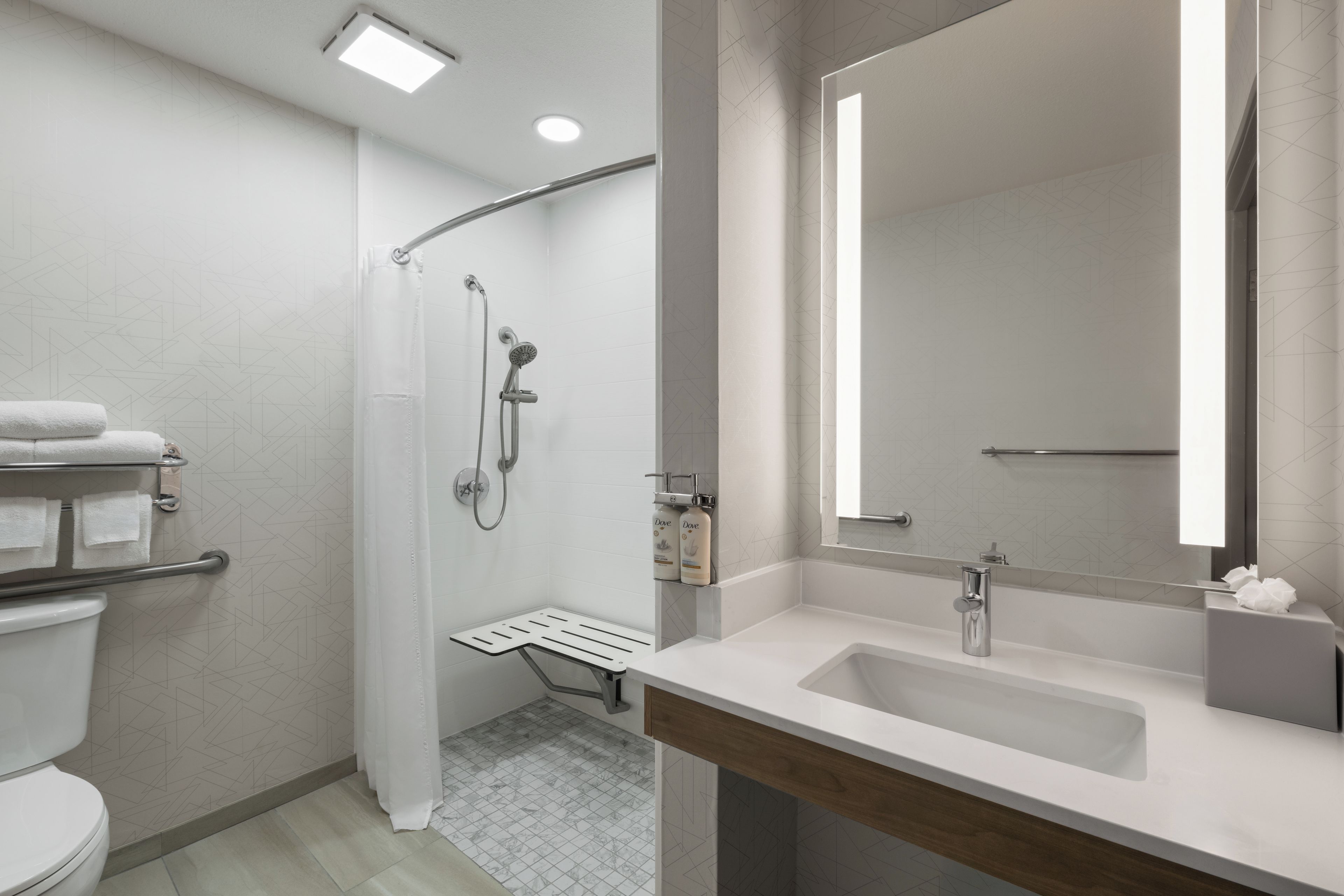 A modern bathroom with a shower, toilet, and vanity.