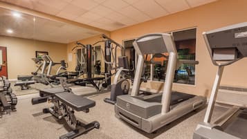 A gym with various exercise equipment including treadmills, weight machines, and free weights.