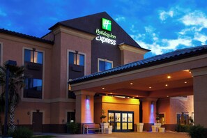 A Holiday Inn Express building with a prominent green logo, a covered entrance, and a well-lit facade. - Holiday Inn Express Hotel & Suites Kingman by IHG (Kingman)