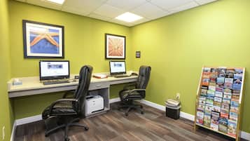 A workspace with two desks, two chairs, a printer, and a bulletin board with magazines.