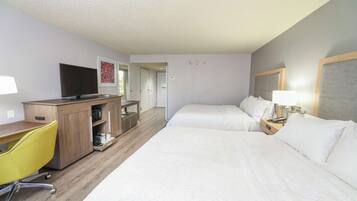 A hotel room with two beds, a desk with a chair, a television, and a wardrobe.