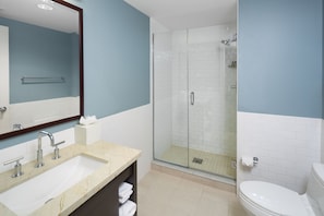 A modern bathroom with a sink, mirror, shower, and toilet.