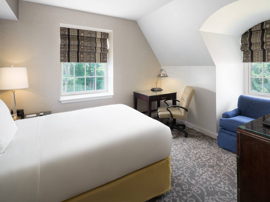 Quarto de hotel com uma cama grande, uma escrivaninha, uma cadeira e um sofá.