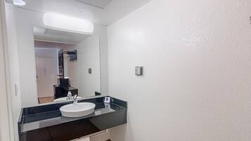 A bathroom with a white sink, a large mirror, and a black countertop.