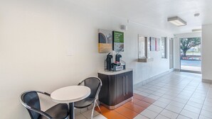 Un hall d’entrée propre et moderne, doté d’un espace café, d’un coin salon et offrant une vue sur l’extérieur.