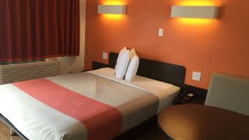 A hotel room with a bed, a bedside table, a chair, and two wall-mounted lights.