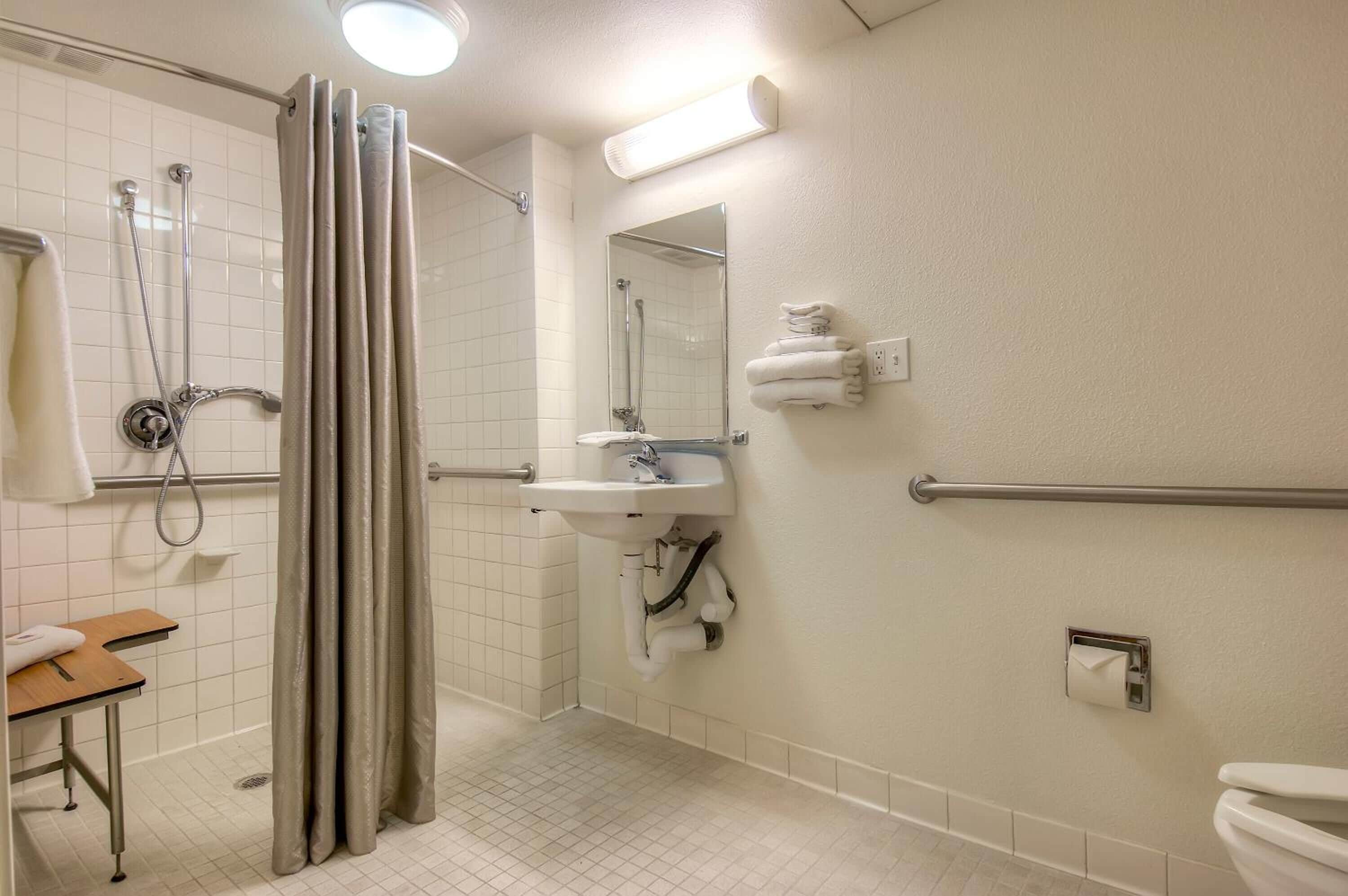 A bathroom with a shower, toilet, sink, and a towel rack.
