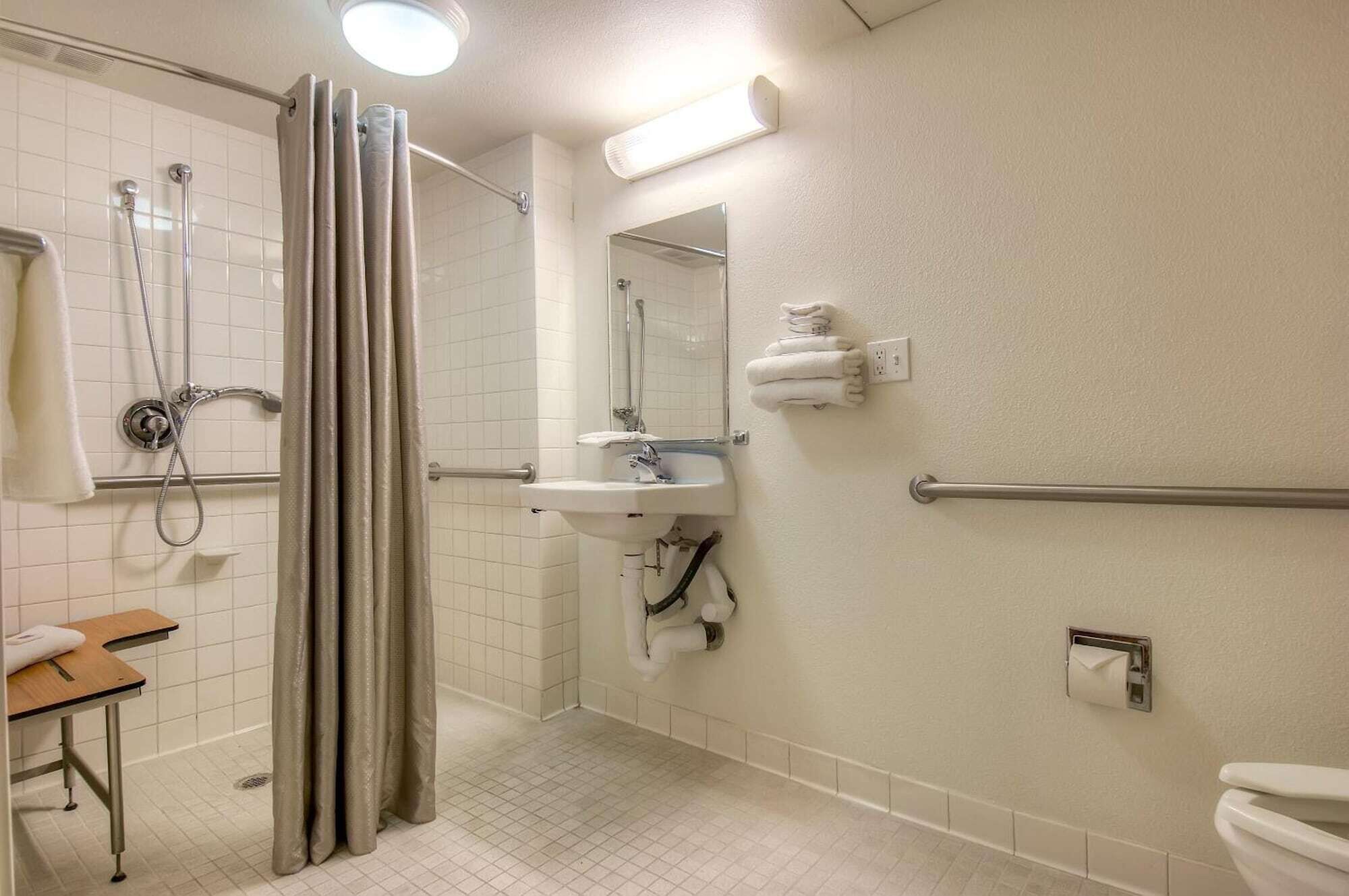 A bathroom with a shower, sink, toilet, and a towel rack.