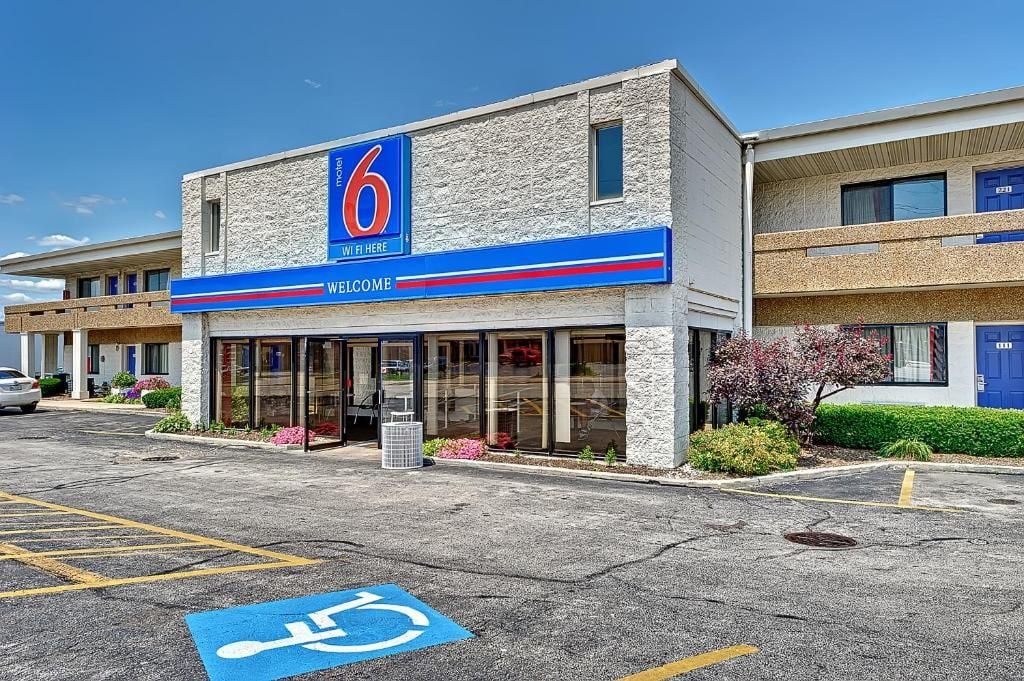 A 6 Motel with a clear entrance, a handicap parking space, and a welcoming sign.