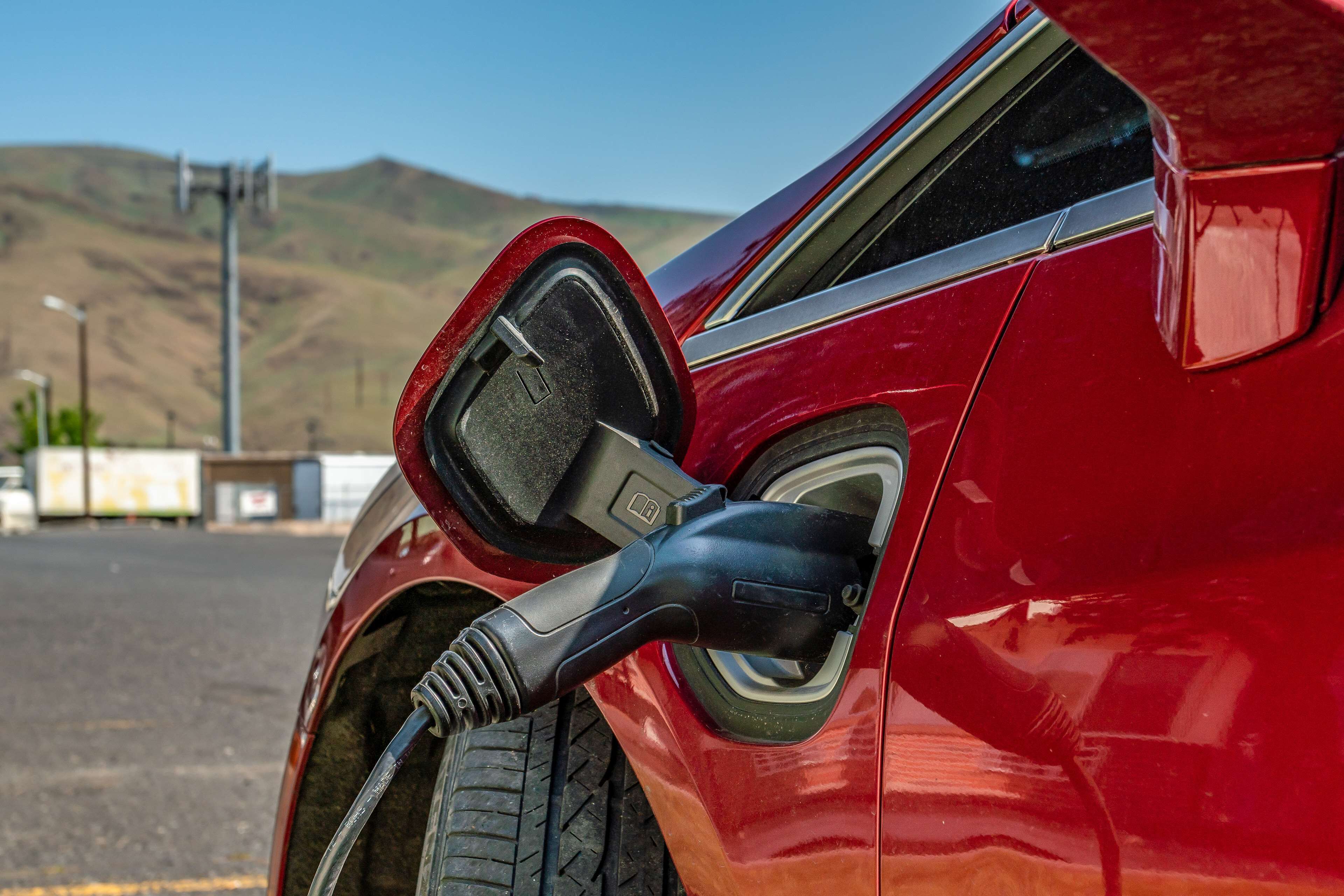 A red car with a charging cable connected to its charging port.