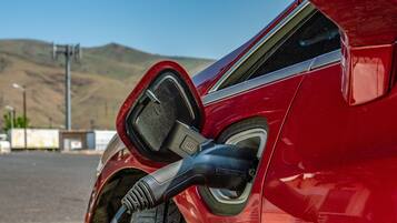 A red car with a charging cable connected to its charging port.