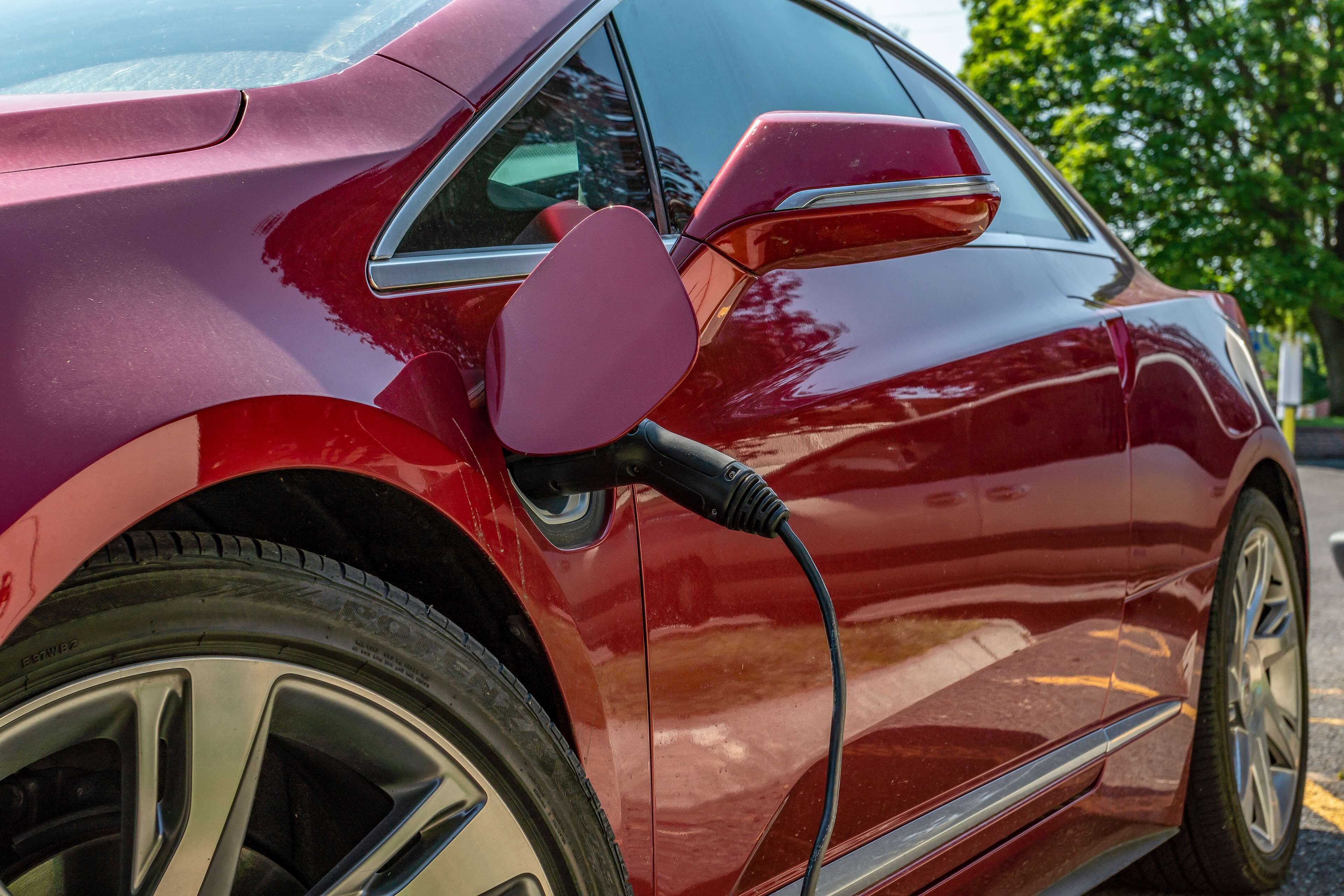 A red car with a charging cable connected to it.