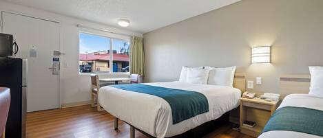 Una habitación de hotel con cama, mesita de noche y escritorio con silla.