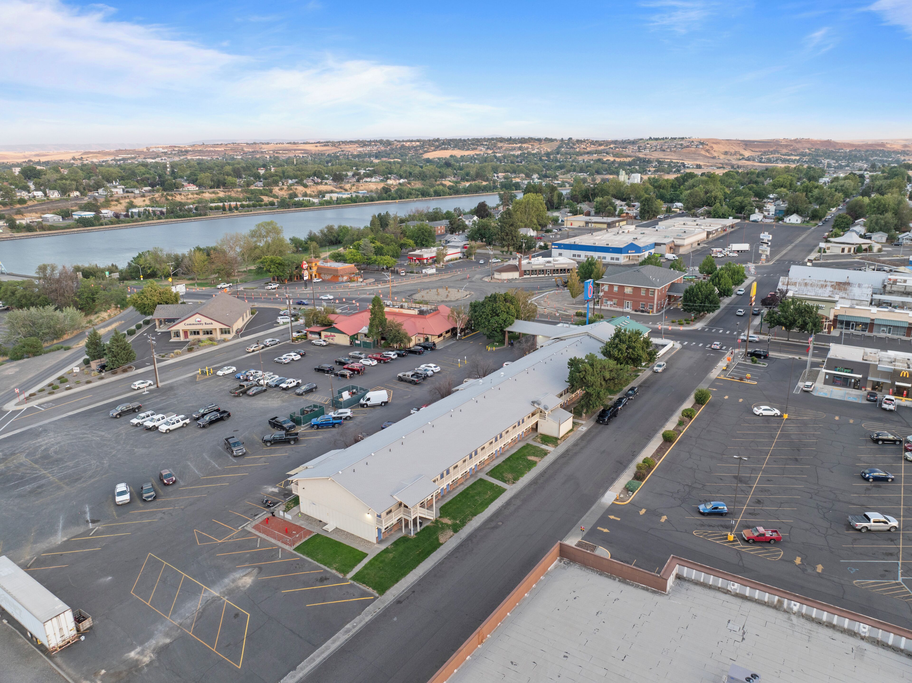 A parking lot with multiple cars and a building with a red roof.