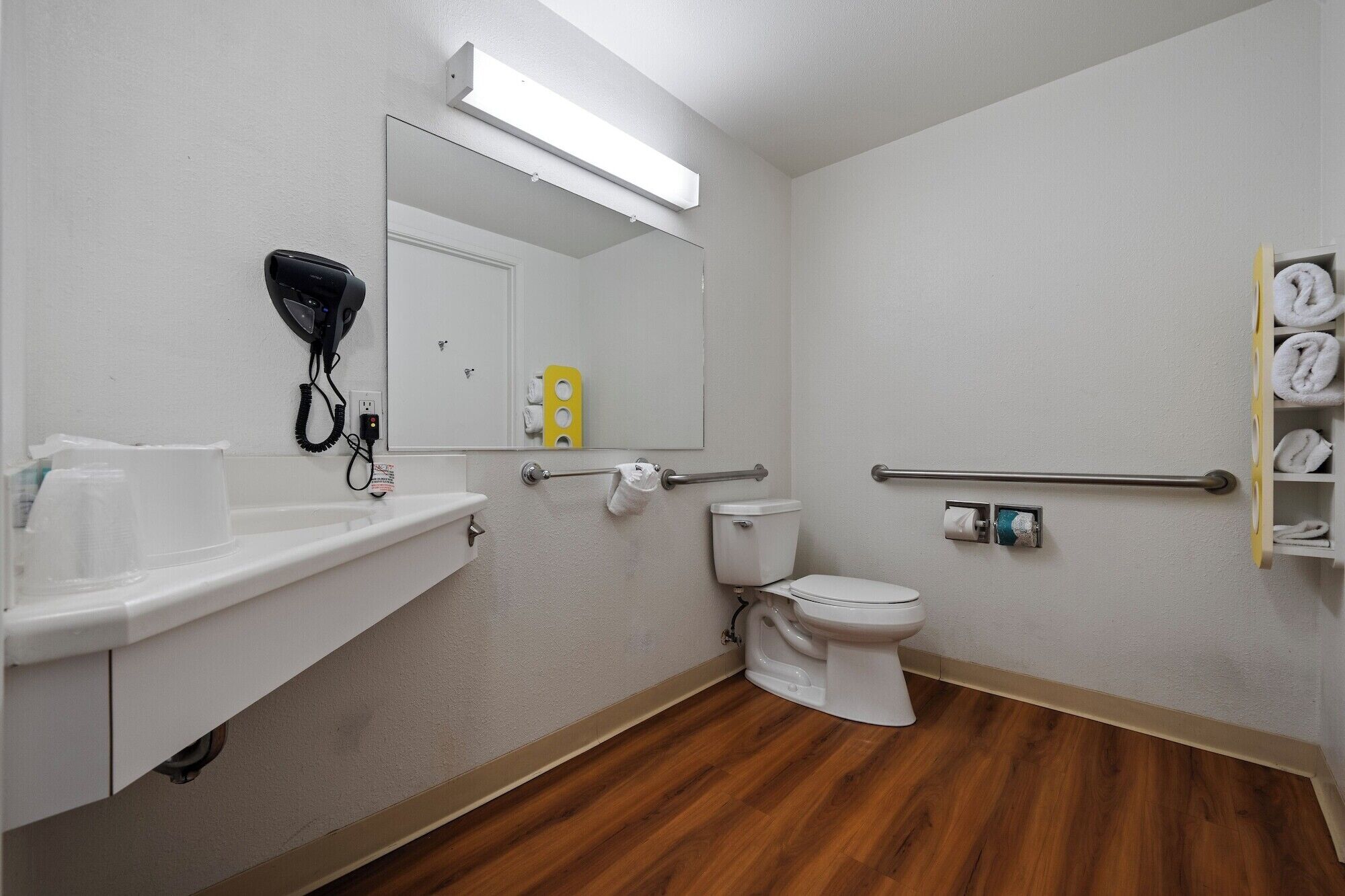 Un baño con lavamanos blanco, inodoro, espejo y toallero.