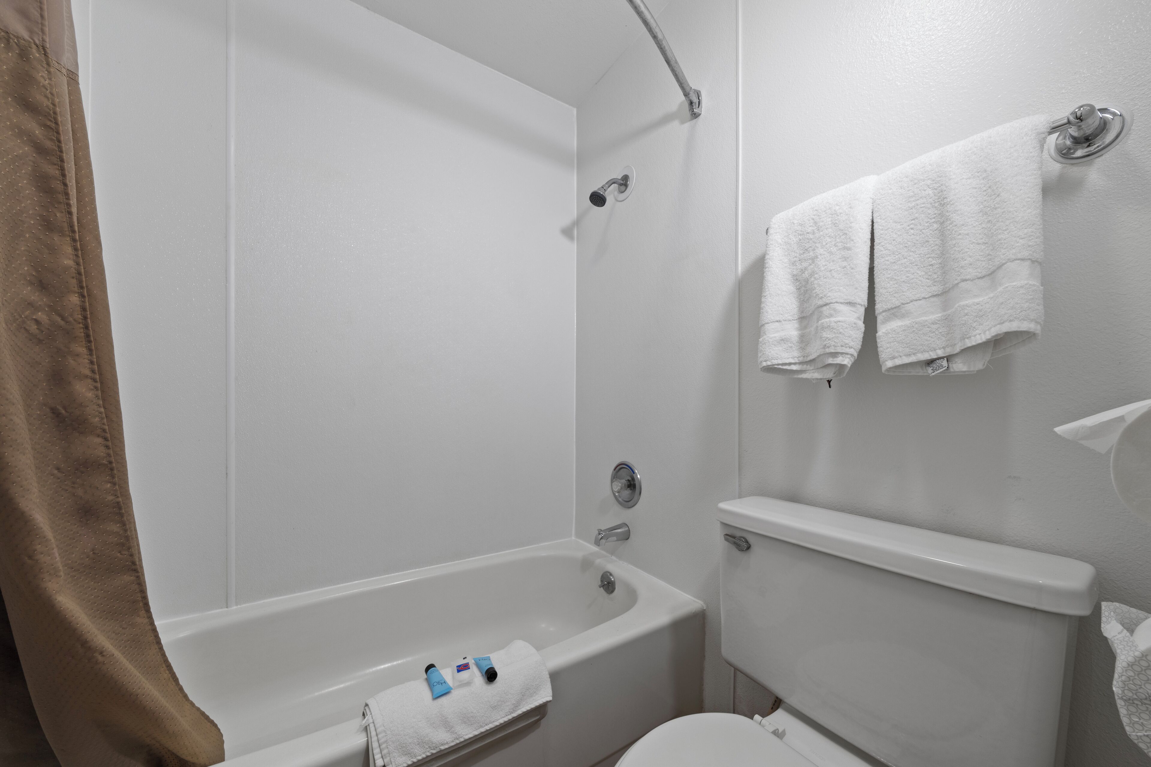 Een badkamer met een bad, toilet en handdoekhouder.