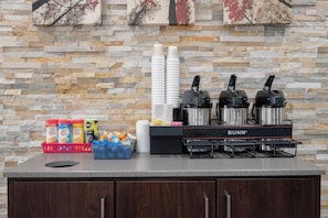 A kitchen area with a stone backsplash, a coffee station with branded coffee products, and a Bunn branded coffee maker. - Red Roof Inn Roanoke Rapids (Roanoke Rapids)