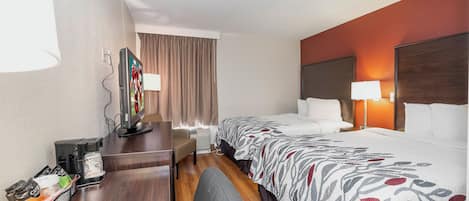 Ein Hotelzimmer mit Bett, Nachttisch, Lampe und Schreibtisch mit einer Kaffeemaschine.