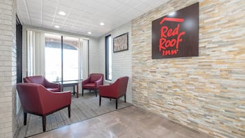 Vestíbulo de Red Roof Inn con pared de piedra, tres sillas rojas y un letrero grande.