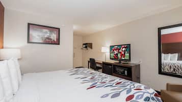 Una habitación de hotel con una cama, un escritorio, un televisor y un cuadro en la pared.