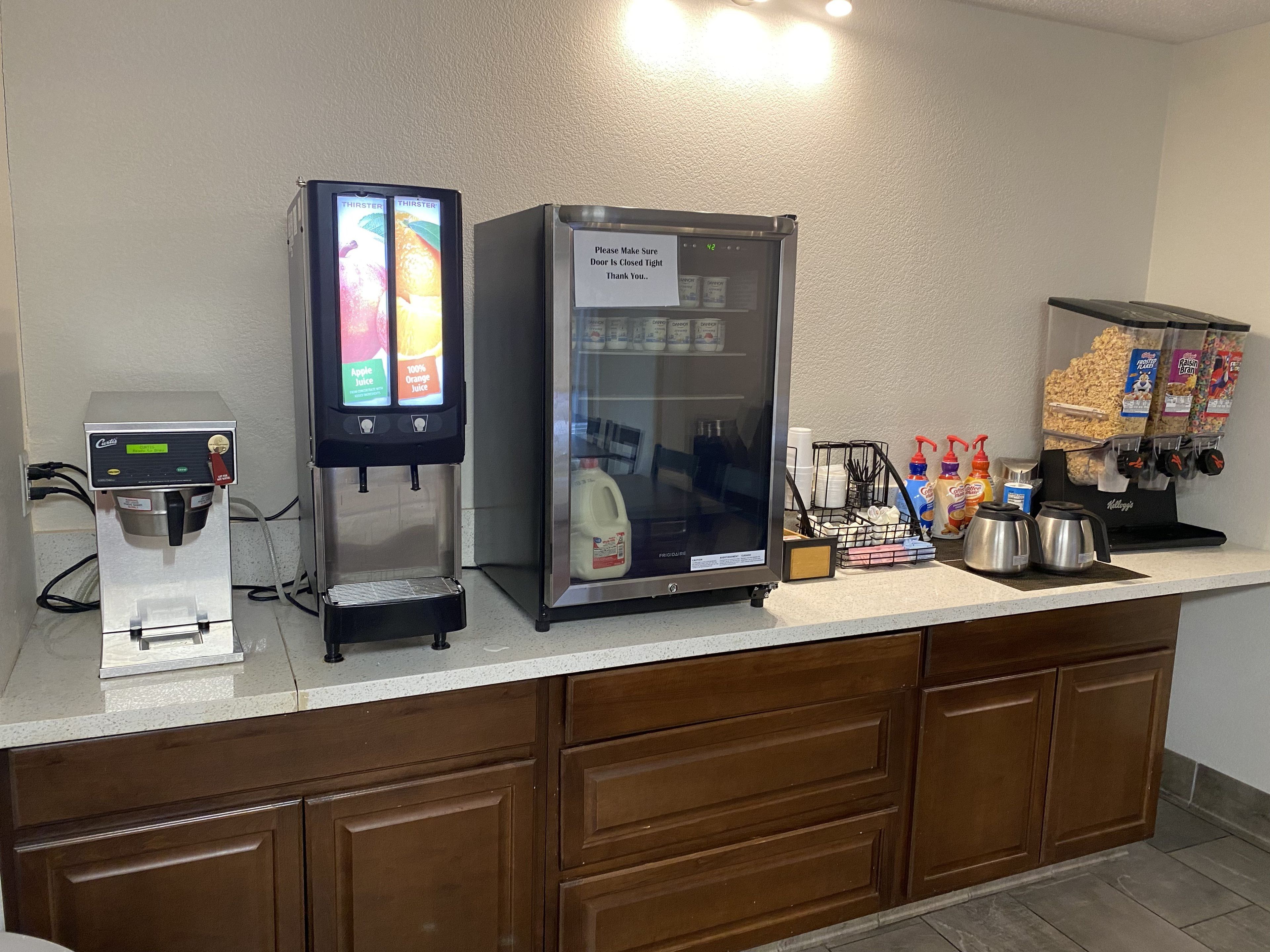 A self-service beverage station with a coffee machine, a refrigerator, and a snack dispenser.