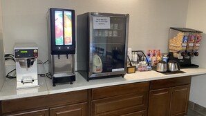 En bemanningsfri dryckesstation med en kaffemaskin, ett kylskåp och en automatt för snacks.