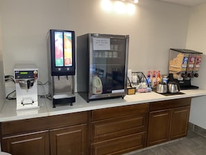 Una estación de autoservicio con máquina de café, refrigerador y dispensador de snacks.