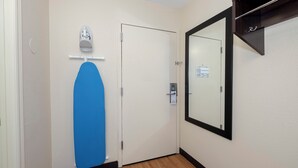 En hall med en vit dörr, en blå matta på golvet, en spegel på väggen och en liten skylt på dörren.