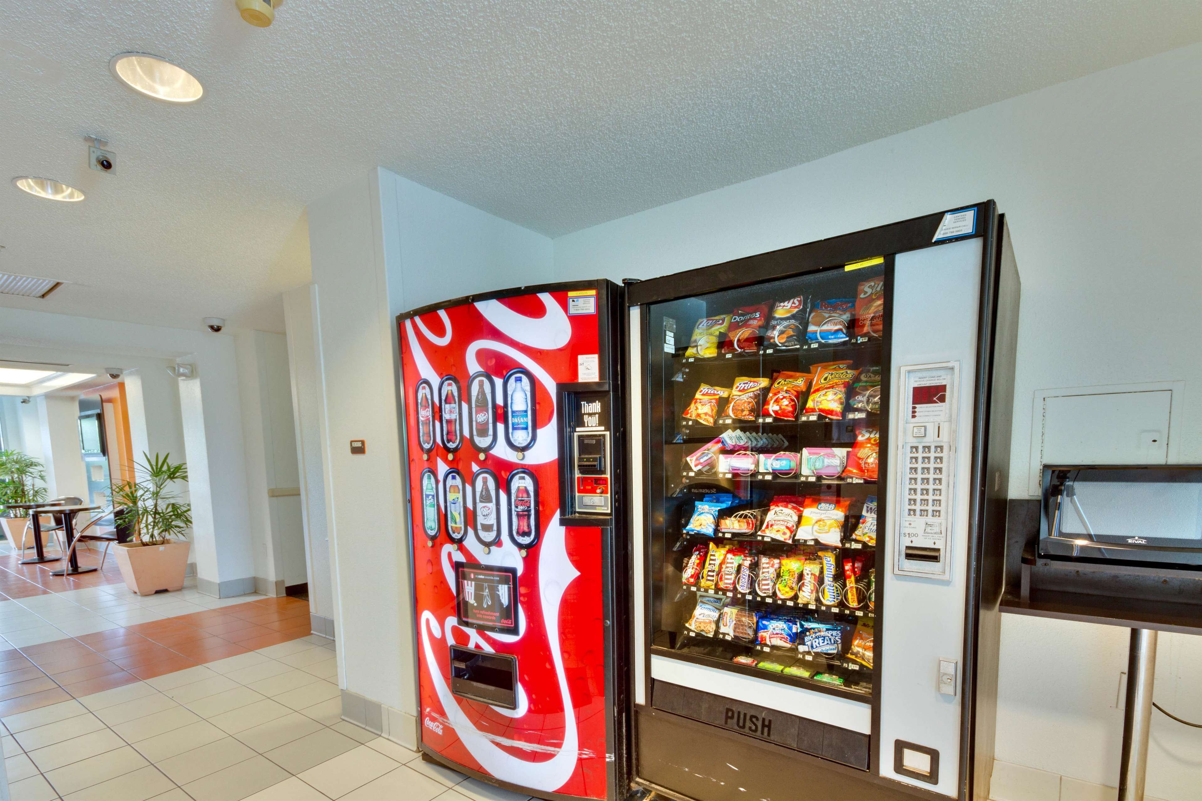 A vending machine with a Coca-Cola logo, a payment terminal, and a selection of snacks and drinks.