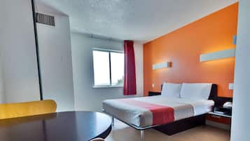 A hotel room with a bed, a desk, and a chair.