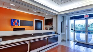 A reception area with a counter, a sign for '6 Motel', and an exit door.