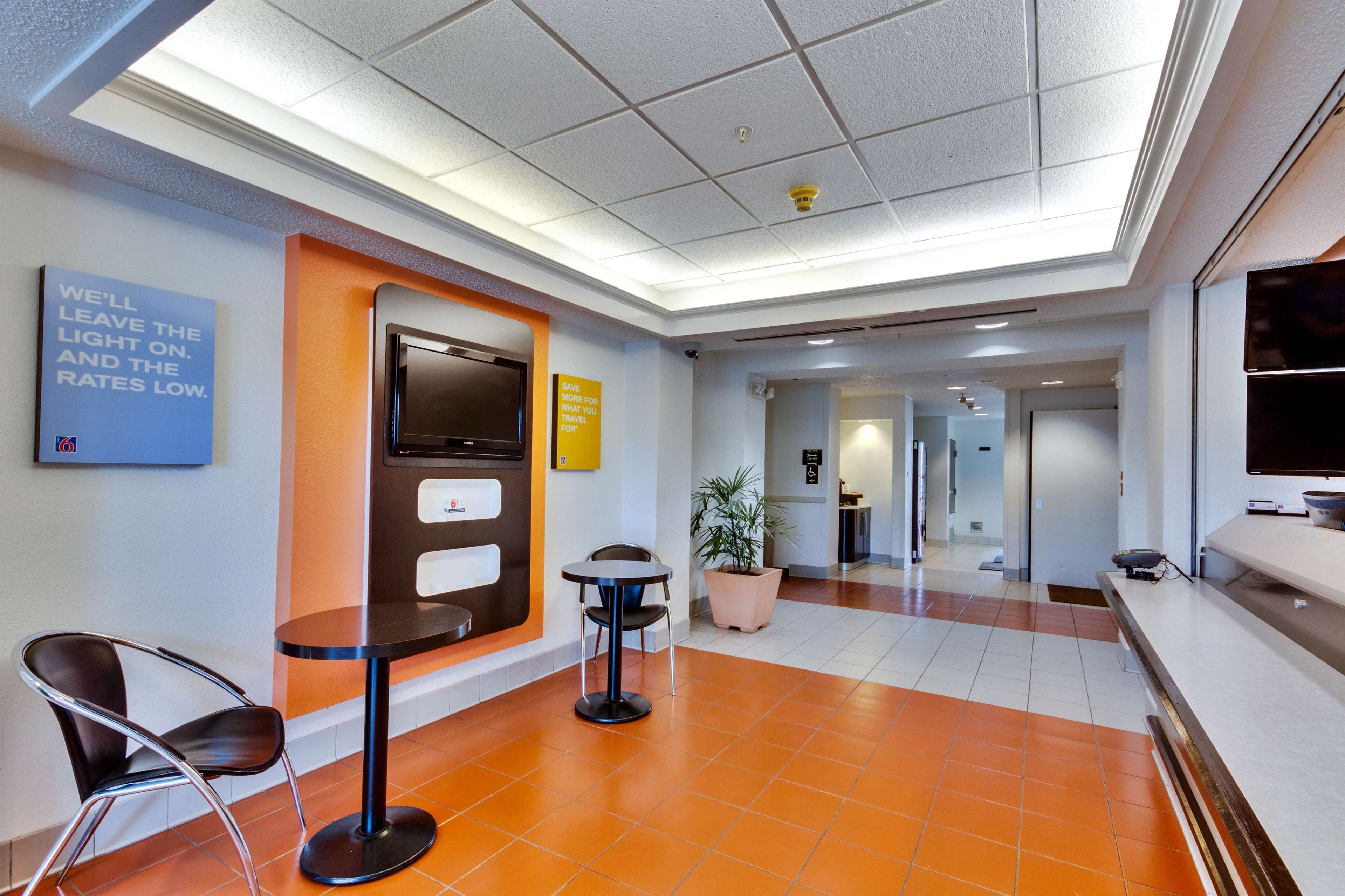 A lobby with a reception desk, a seating area with chairs, a potted plant, and a sign on the wall.