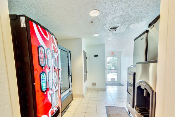A hotel corridor with vending machines, a water dispenser, and an exit sign.