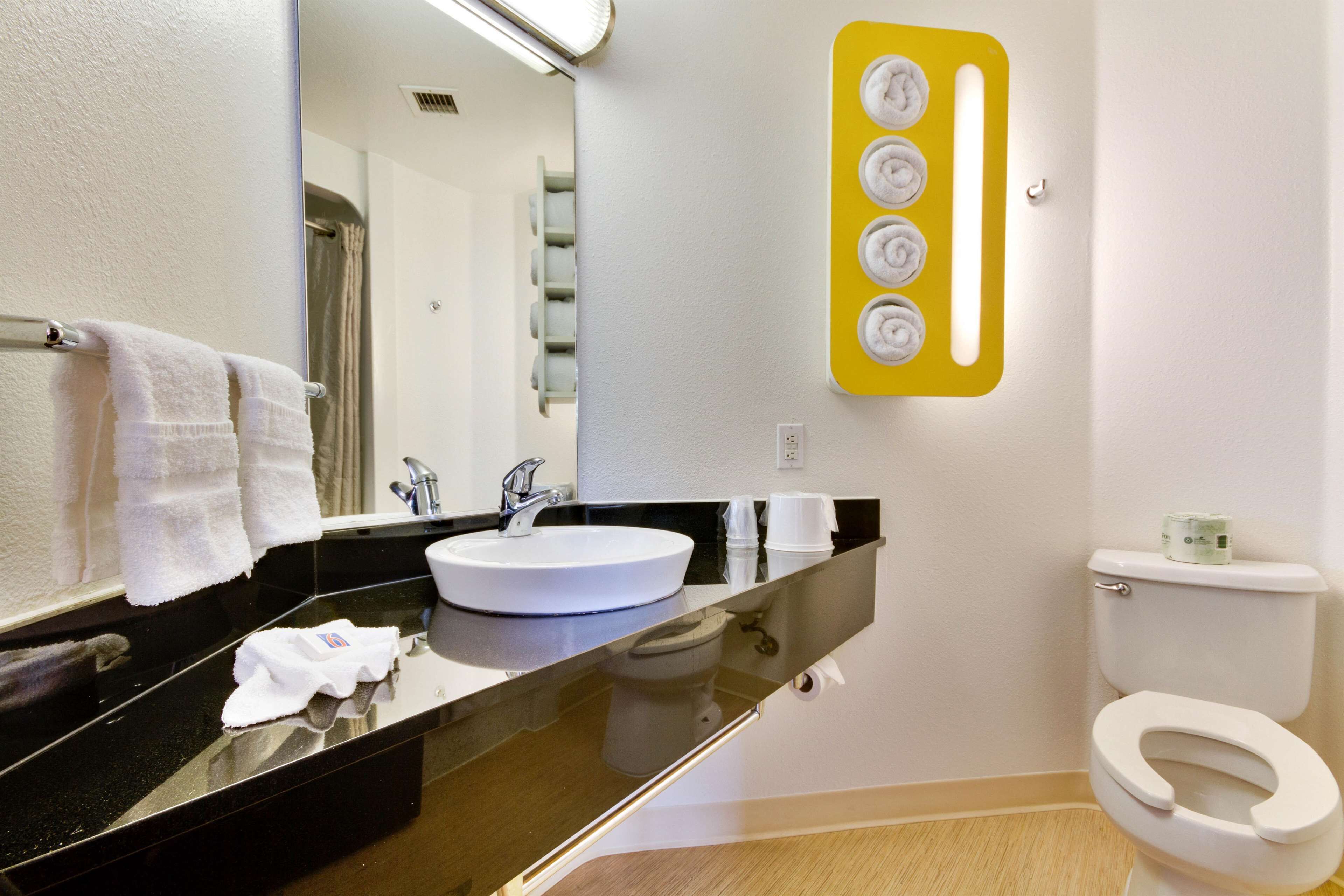 A bathroom with a white sink, black countertop, and a toilet.