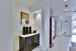 A modern kitchen with a coffee station, a large refrigerator, and a wall-mounted mirror.