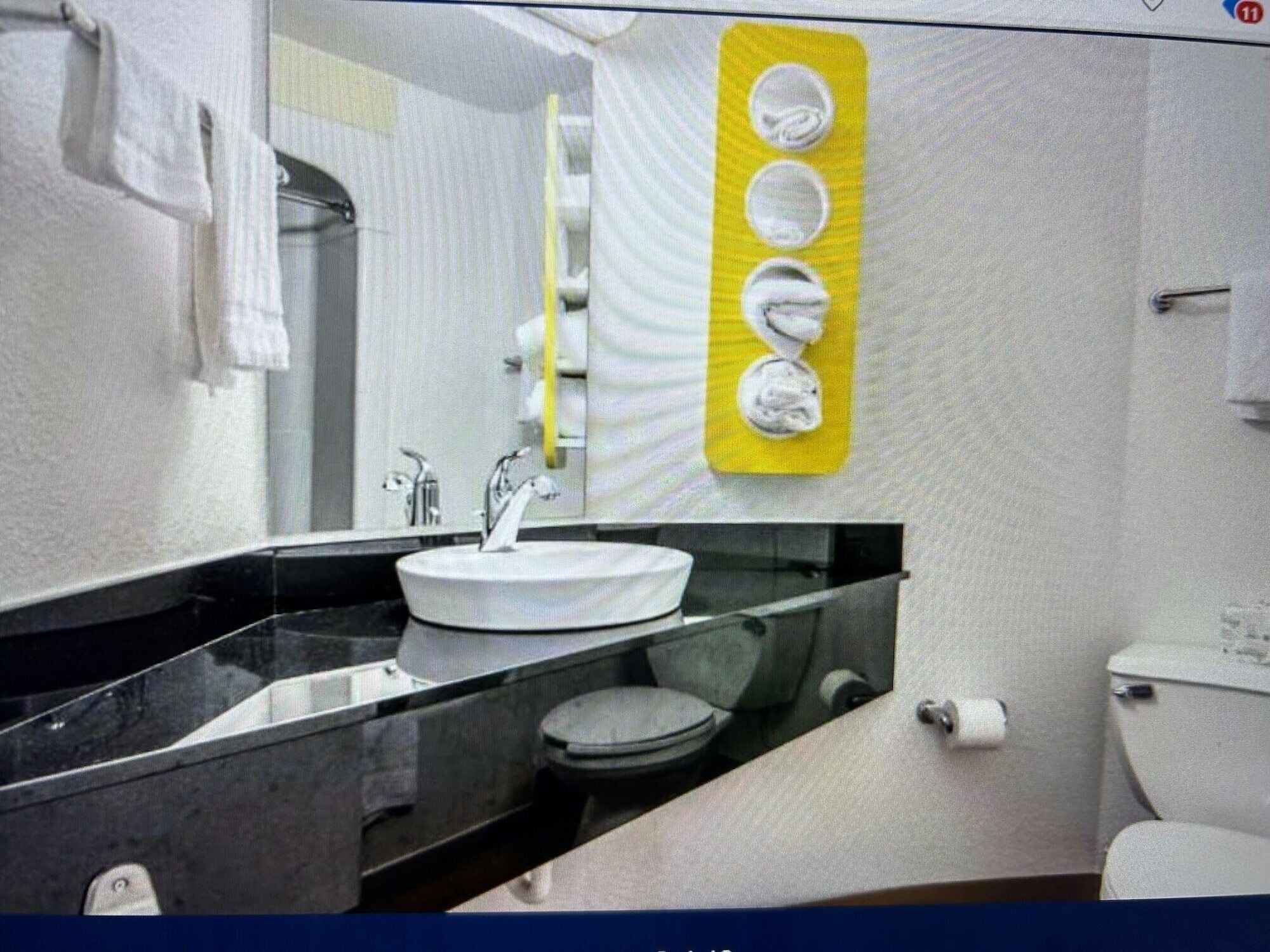 A bathroom with a white sink, black countertop, and a yellow soap dispenser.