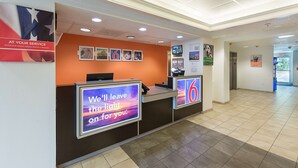 A hotel reception area with a reception desk, a large number '6' sign, and a banner offering discounts to active and retired military personnel. - Motel 6 Columbia, SC - Fort Jackson Area (Columbia)