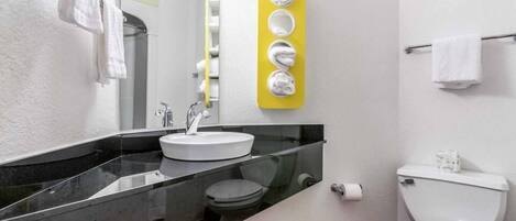 Un baño moderno con encimera negra, lavamanos blanco y toallero amarillo, además de un inodoro.