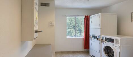 A laundry room with a washing machine, dryer, and a table.
