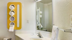 A bathroom with a white sink, a mirror, and a yellow towel rack with five towels.