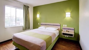 A hotel room with a bed, a window with curtains, and two wall-mounted lights. - Super 8 by Wyndham Aurora East (Aurora)