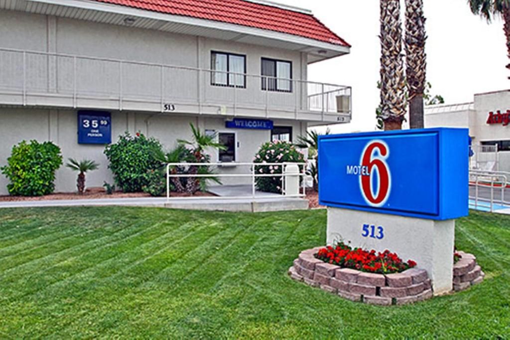 A motel with a blue sign indicating it is number 513, a red roof, and a well-maintained lawn with red flowers.