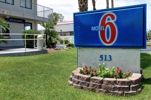 A motel sign with the number 513 and the name 'Motel 6' in front of a building with a balcony and a 'WELCOME' sign.