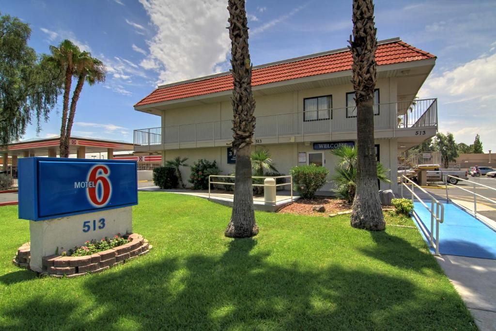 A motel with a red-tiled roof, a sign indicating it's number 513, and a blue sign for the motel.