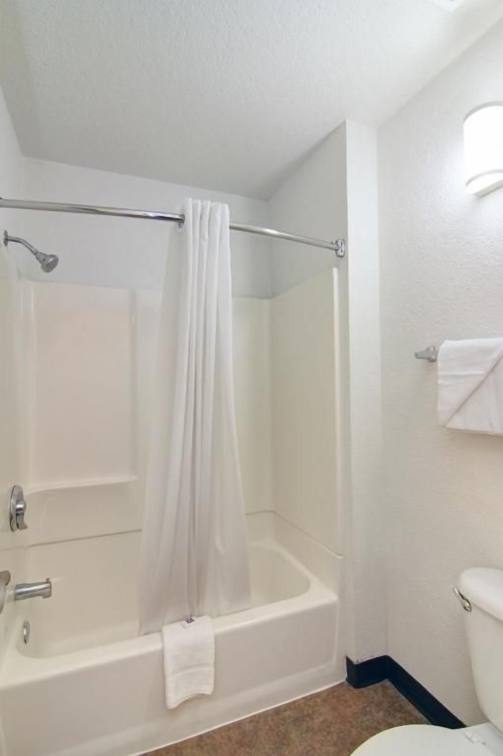 A bathroom with a bathtub, a shower curtain, a toilet, and a towel rack.
