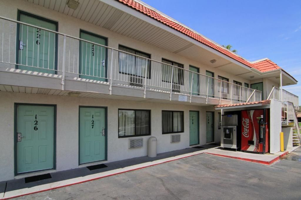 A two-story motel with numbered doors, a Coca-Cola vending machine, and a small outdoor area.