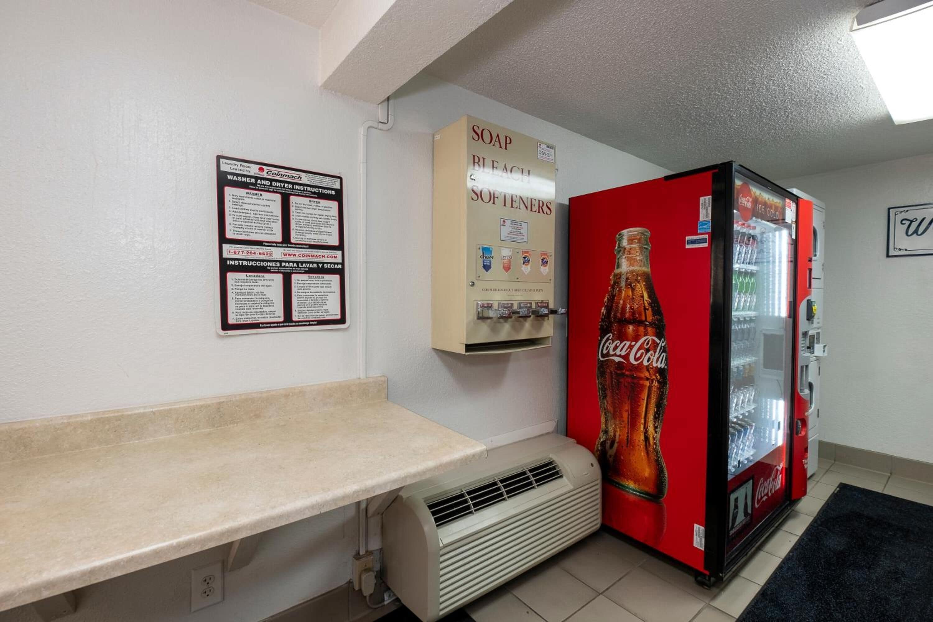 Una habitación con máquina expendedora, dispensador de jabón y refrigerador de Coca-Cola.