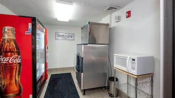 A compact kitchenette with a refrigerator, microwave, and a Coca-Cola refrigerator.