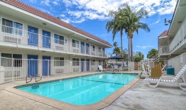 Un hotel con piscina, varios balcones y palmeras.